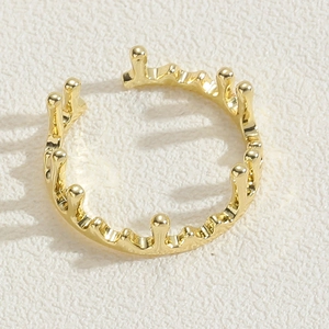 Makroaufnahme eines goldenen Kronenrings mit Schmelztextur auf beigem strukturiertem Papier