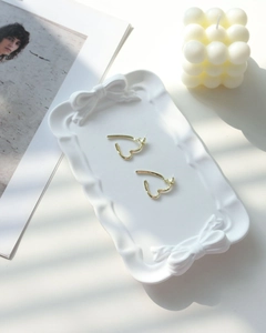 Detailed view of golden stylized heart earrings on a decorative bow plaster tray