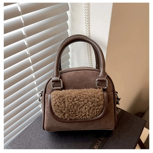 Detail of brown faux suede handbag with plush wool trim and metallic buckle accents