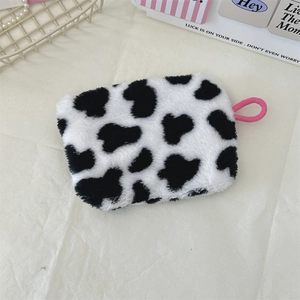 Close-up of cow print plush coin purse featuring a vibrant pink strap and fuzzy texture