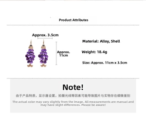 Detailed view of long purple shell fish earrings with gold hooks and scale texture