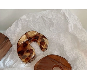 Detail view of large leopard print hair claw clips on white textured background