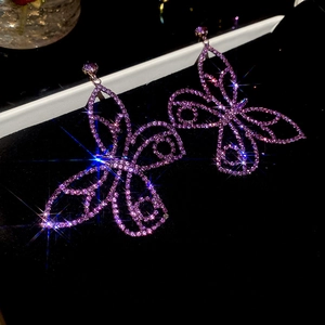 Macro shot of purple butterfly earrings with sparkling crystals and shimmering star flares