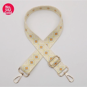 Detailed view of adjustable wide polyester bag strap with geometric pattern and gold hooks.