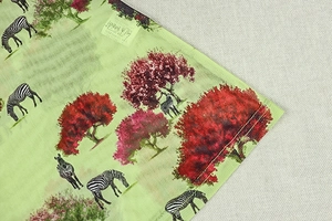 Dettaglio dell'orlo dell'abito verde chiaro con motivi di zebra e alberi rosa