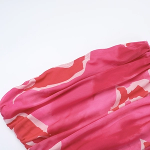 Gros plan sur une robe en mousseline imprimée rose et rouge avec frous-frous