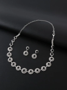Detailed view of silver necklace and earrings set with black stones and white crystals