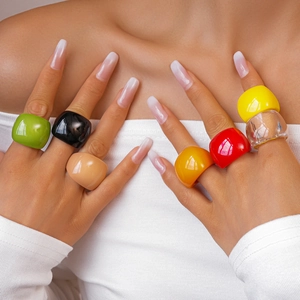 Close-up of vibrant chunky resin rings in multiple colors worn by a female model