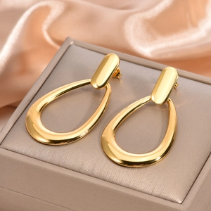 Detailed view of long gold drop earrings featuring a sleek oval hollow design on satin fabric