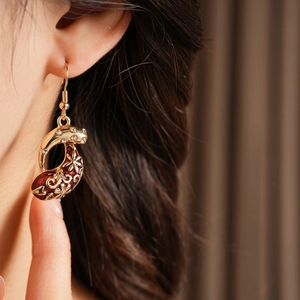 Detail of teardrop vintage earring with red enamel and floral zircon inlay on model