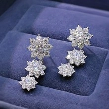 Detailed view of silver flower earrings with white zircons in a navy velvet jewelry box