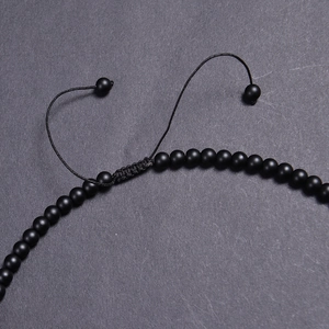 Macro detail of the black matte beads and adjustable braided nylon sliding knot