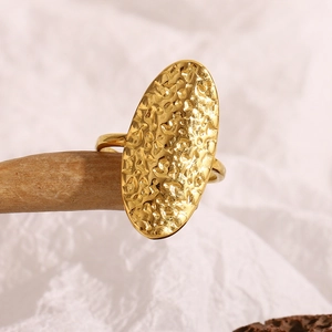 Macro detail of hammered gold oval signet ring featuring vintage industrial texture