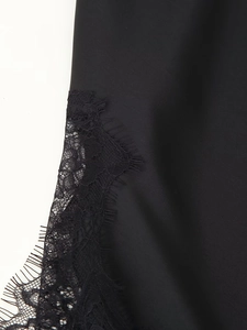 Detailansicht von schwarzem Satinstoff mit zarter Wimpernspitze und feinen Nähten