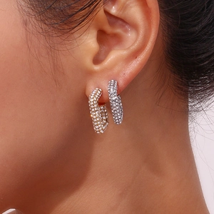 Primo piano di orecchini a U in oro e argento con zirconi cubici indossati da una modella