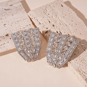 Detailed view of silver fan-shaped statement earrings with zircons on textured stone