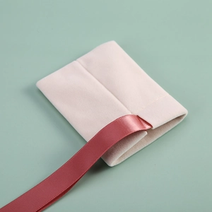 Detail of pink velvet jewelry pouch with dark rose ribbon on a mint green background