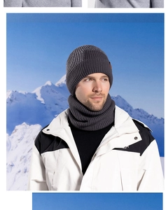 Détail du tricot de l'ensemble bonnet d'hiver et cache-col gris foncé devant la neige