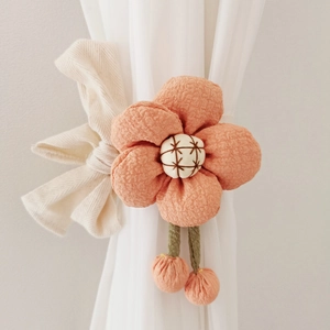 Detail of orange fabric flower curtain tieback with embroidery and small tassels