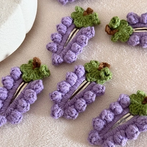 Dettaglio di fermagli per capelli a uva lavorati a mano con filato viola e clip BB