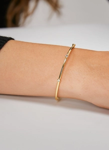 Detailed view of an adjustable gold brass bracelet with three sparkling white zircons on a wrist