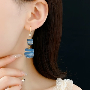 Detail of bohemian earring with blue cubic beads and gold stripes on model's ear
