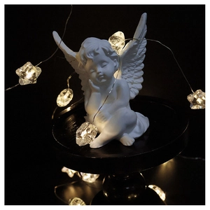 Detailed view of white angel sculpture with warm star LED string lights decoration