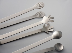 Detail of stainless steel sugar tongs featuring shell and hand shaped serving ends
