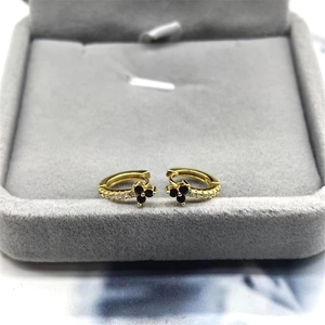 Elegant gold earrings with black flower pendants and white zircon on gray velvet box