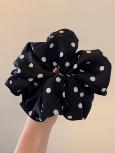 Close-up of black and white polka dot fabric scrunchie with Balmain designer label