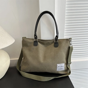 Dettaglio della borsa tote in tela verde militare con manici neri in ecopelle ed etichetta