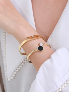 Close-up of elegant gold open bangles with crystal pavé and monochrome disc detail