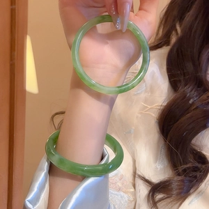 Close-up of dual emerald green resin bangles with a smooth polished finish on a wrist