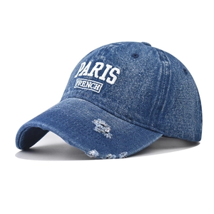Detailed view of the distressed brim and white Paris embroidery on washed denim cap