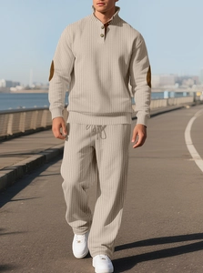 Outdoor shot of men's beige ribbed knit tracksuit with brown elbow patch details