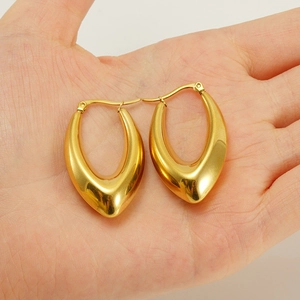 Detailed close-up of chunky gold U-shaped earrings with a high-polished mirror finish