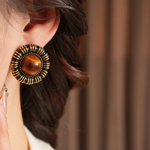 Close-up of vintage round stud earrings with cat-eye stone and textured gold frame