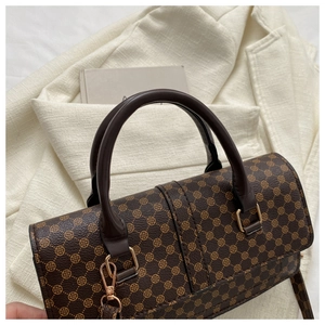 Detailed close-up of dark brown monogrammed texture and gold hardware on handbag