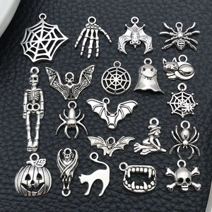 Detailed macro view of 19 assorted antique silver Halloween charms on black texture
