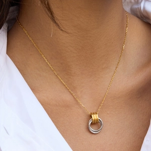 Close-up of dual-tone interlocked geometric circles pendant on a gold cross chain