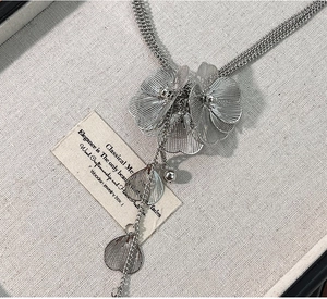 Close-up of silver hollow floral pendants and leaf tassels on a vintage metal necklace