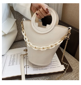 Detail of white bucket bag featuring unique circular handle and chunky decorative chain