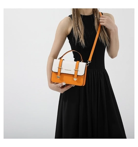 Detail view of structured orange and white contrast crossbody bag with top handle
