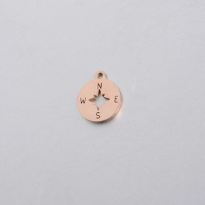 Macro detail of rose gold compass pendant with hollow star and engraved direction letters