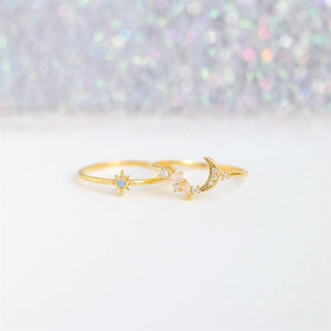 Detailed view of gold star and moon rings with blue and pink cubic zirconia stones