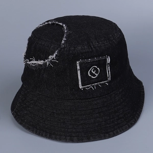 Detailed close-up of distressed denim fabric and letter f embroidery on black bucket hat