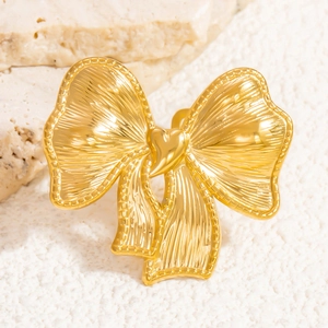 Close-up of golden bow-shaped ring with textured surface and heart detail