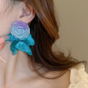 Detail of gradient resin flower and blue satin bow earring worn by a model