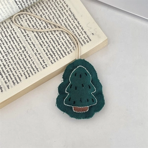 Detail van handgemaakte groene stoffen kerstboom hanger met borduursel op een oud boek