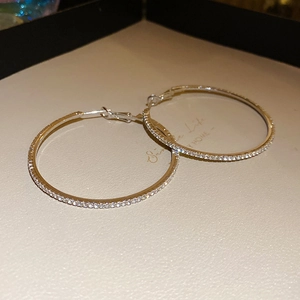 Detail view of large silver hoop earrings with shimmering white cubic zirconia stones